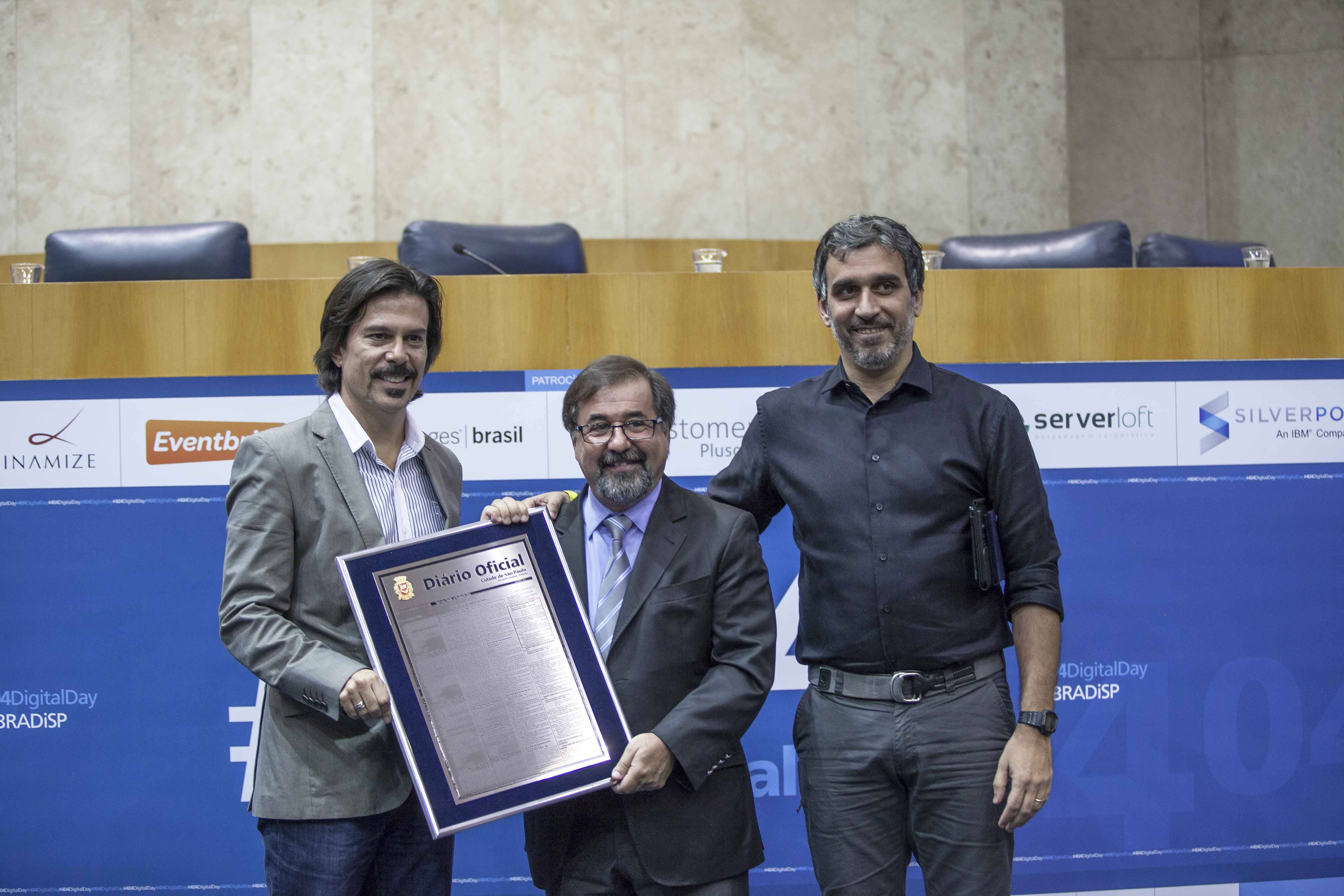 Bernardo Castello Branco (esq), presidente ABRADi-SP recebe reprodução do Diário Oficial com Lei #404DigitalDay do Vereador Marco Aurélio Cunha e de Alexandre Suguimoto, vice presidente